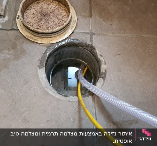 צינורות צהובים ואפורים בתוך פתח ביוב על רצפה